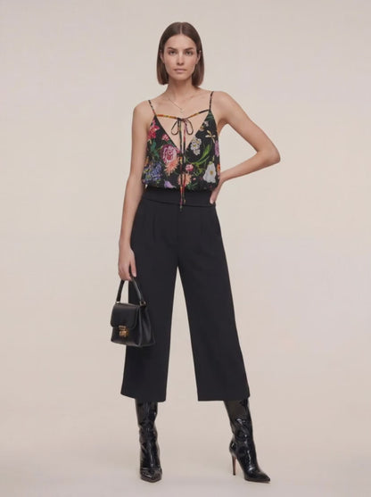 Femme portant un Haut en soie et pantalon noir trois quart et un sac en cuir à la main